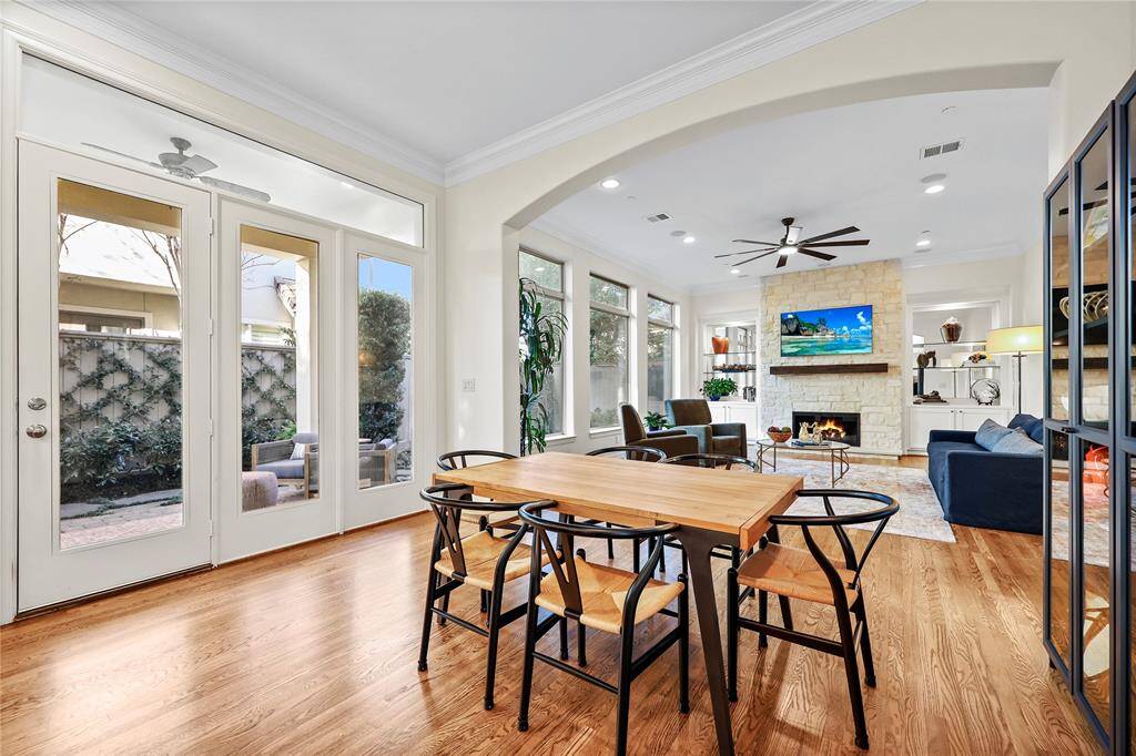 Bright and inviting open-concept living space features a seamless flow between the dining and living areas. Expansive windows and French doors allow natural light to flood the space while providing a picturesque view of the outdoor patio.