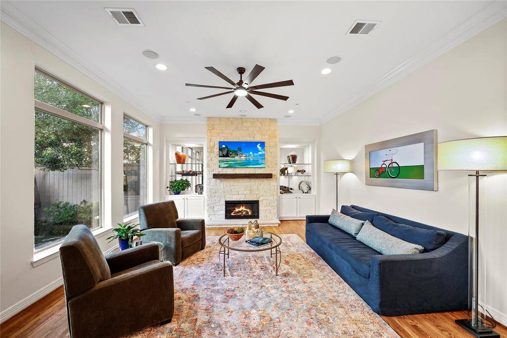 This inviting room features rich hardwood flooring and a layout that seamlessly connects to the breakfast area. Floor-to-ceiling windows flood the space with natural light
