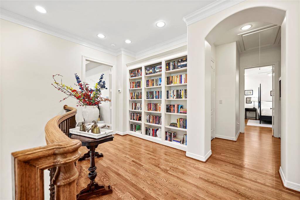 Ascending the staircase with rich wood treads, you are welcomed to a spacious and inviting second-floor landing. This thoughtfully designed area features a striking wall of bookshelves, offering both storage and a stylish display for books and decor