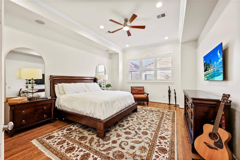 The elegant primary suite is a serene retreat featuring rich hardwood floors and recessed lighting