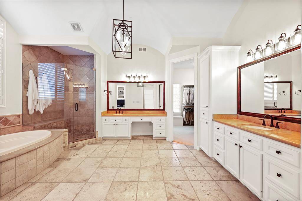 This grand, spa-like primary bath is a true retreat, featuring tumbled travertine flooring, a striking groin-vault, and timeless finishes throughout