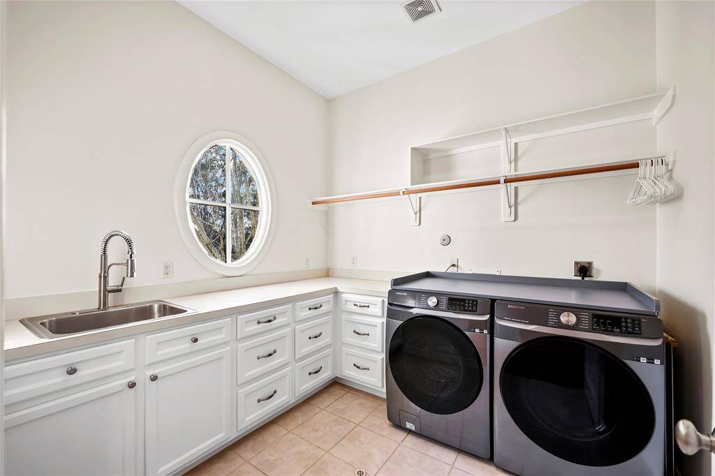 Located on the second floor, this spacious utility room offers ample counter space, abundant cabinet and drawer storage, a built-in sink, and a convenient hanging rod.