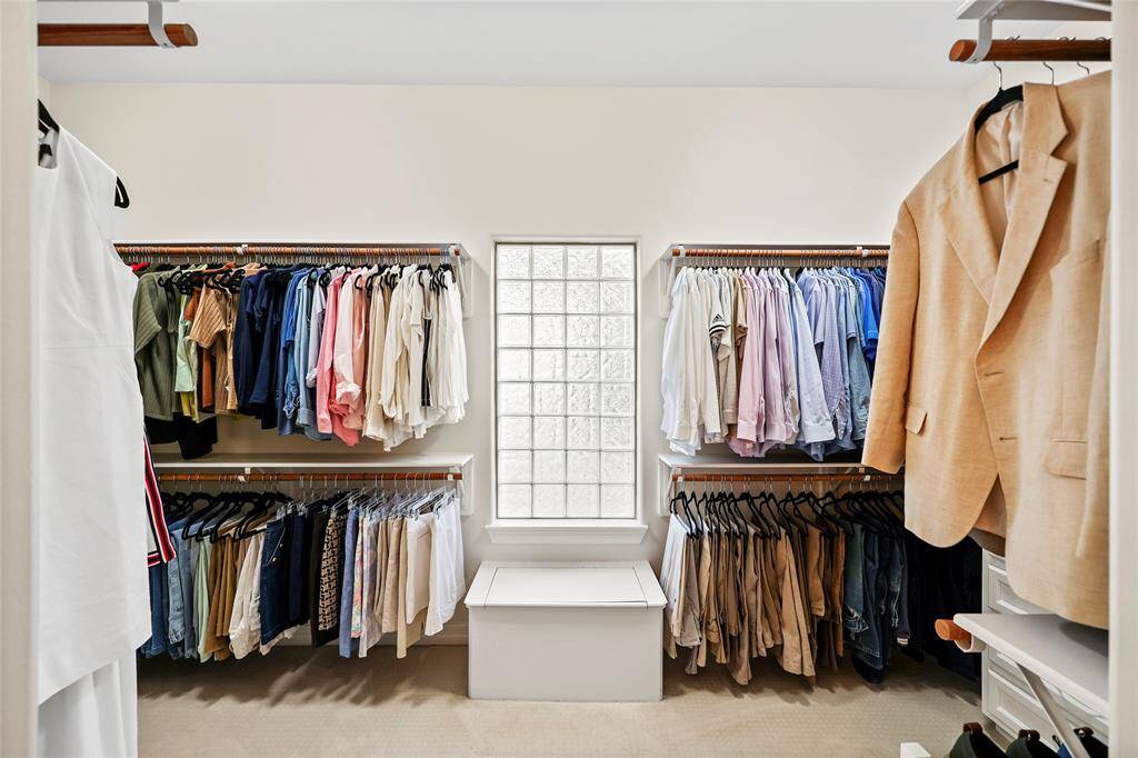 Thoughtfully designed for organization and convenience, this expansive walk-in closet offers custom built-in shelving, ample hanging space, and a central storage bench