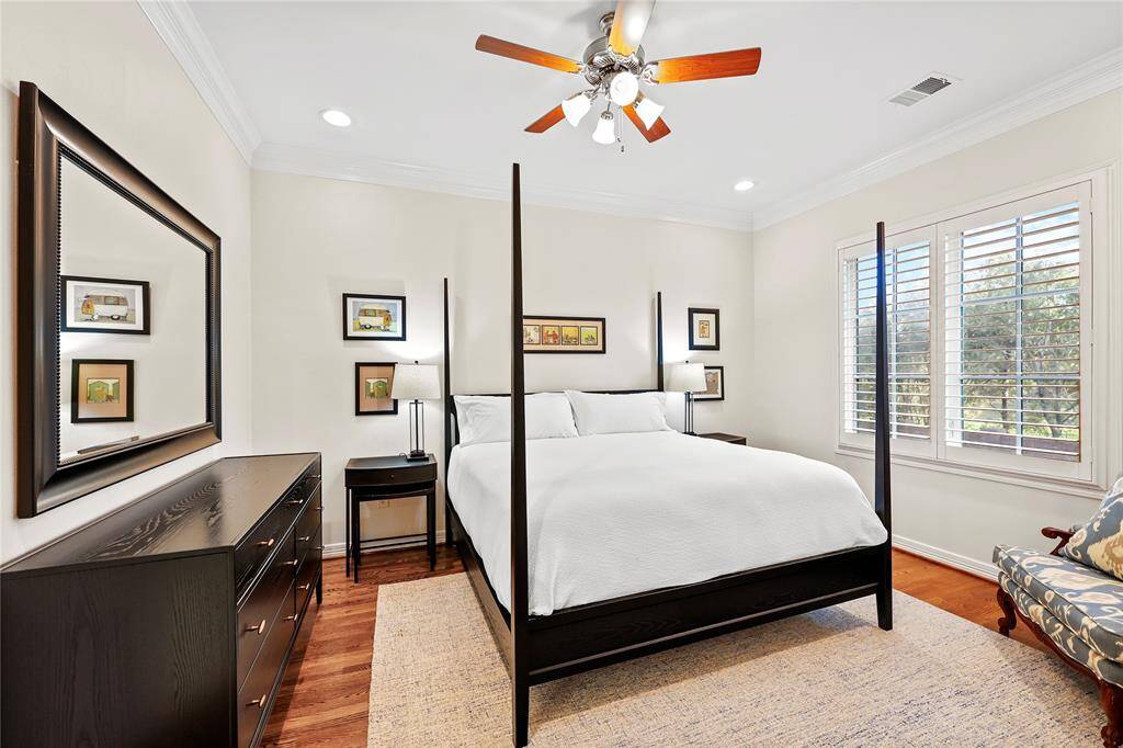 Generous secondary bedroom boasts hardwood floors, an 11-foot ceiling, and a large window with custom shutters overlooking the front yard. It also features a walk-in closet and an ensuite bath