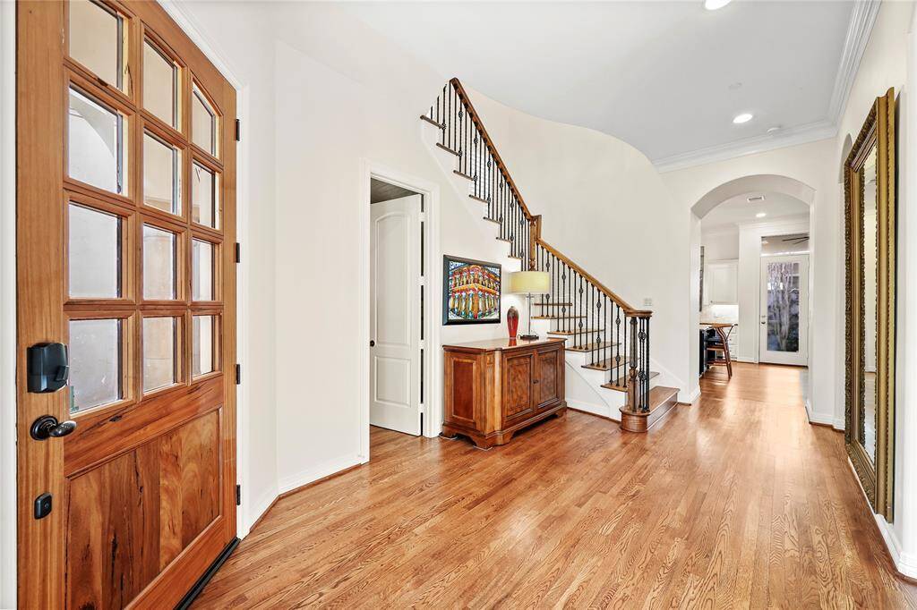 The foyer welcomes you with soaring 11-ft ceilings, an abundance of natural light,and warm hardwood floors. A grand staircase with wrought iron railings and hardwood treads