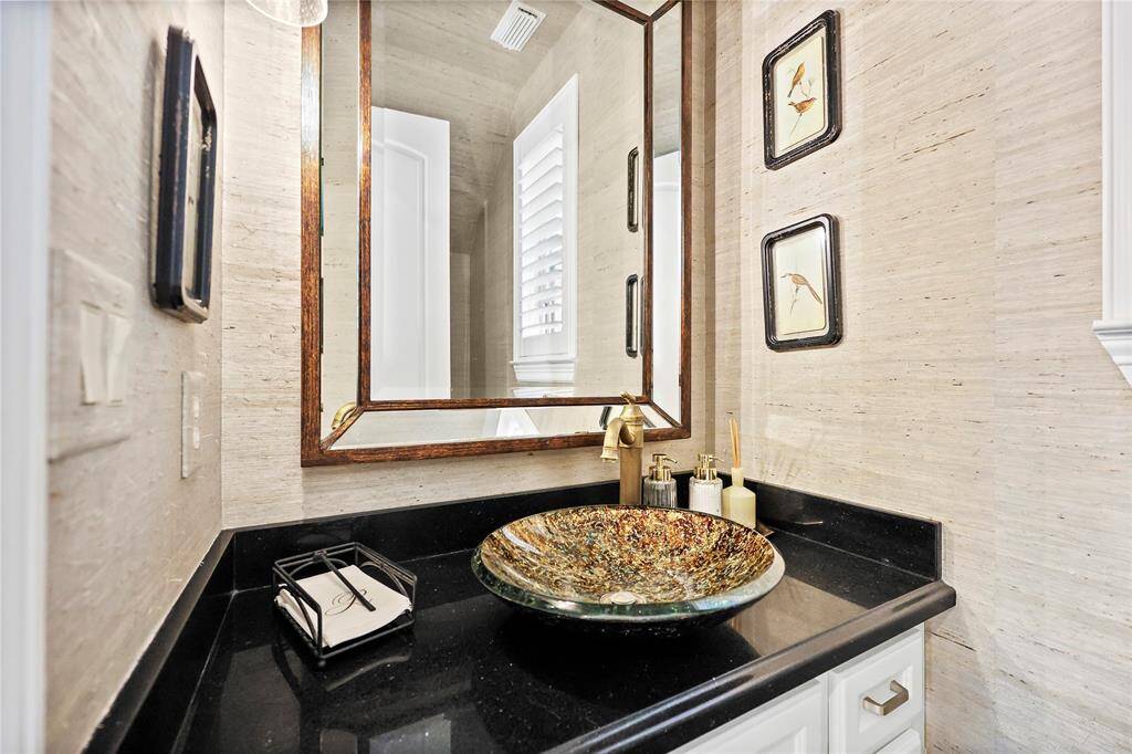 This sophisticated powder bath, conveniently located off the foyer, showcases timeless elegance with its rich hardwood flooring and textured grasscloth wallpaper.