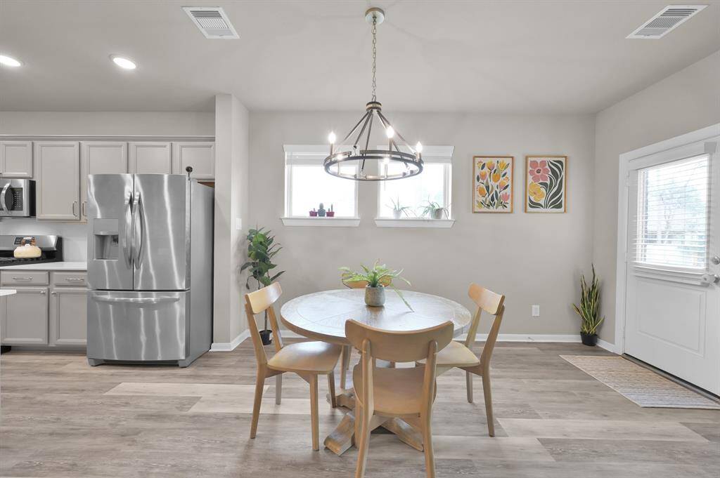 The spacious dining room is perfectly located between the kitchen and living room. The elegant light fixture helps to distinguish the room. You can easily fit a larger table in this space.