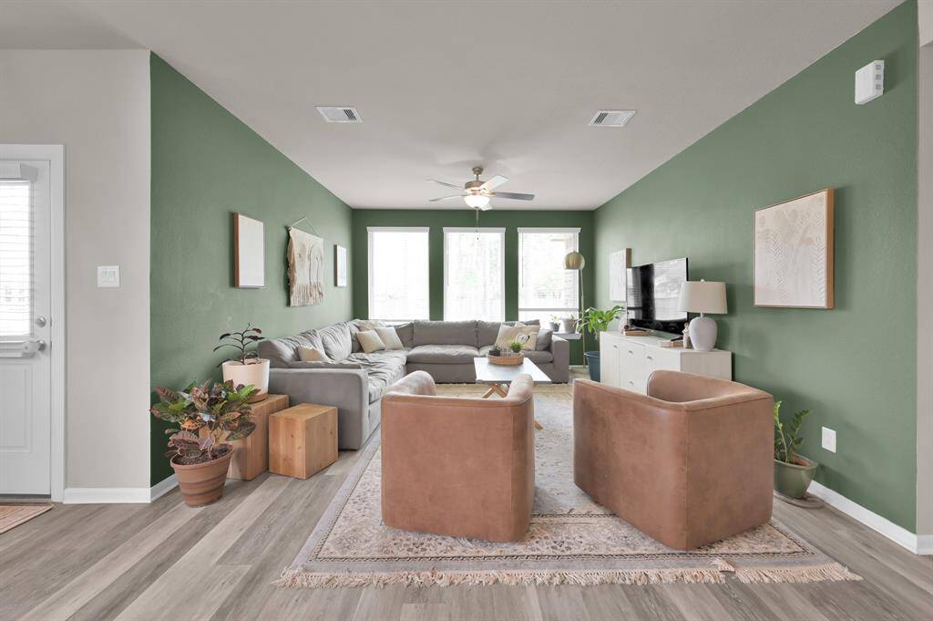This bright and airy living room showcases an accented green wall and offers an abundance of natural light, creating a warm and welcoming space perfect for relaxing or entertaining