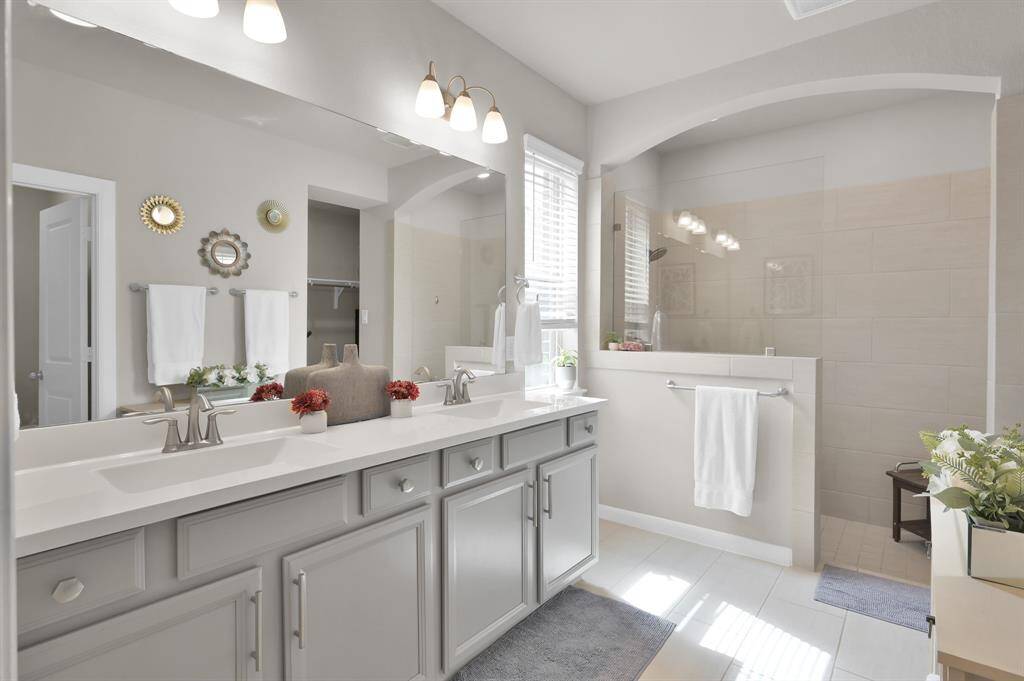This stunning bathroom features sleek gray cabinets with modern hardware, a spacious shower, and abundant natural light.