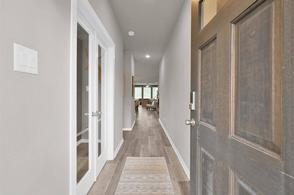 Upon entering you're greeted with a formal entry hallway, wood-look luxury vinyl plank flooring, French doors to the office, and a view into the bright living room.