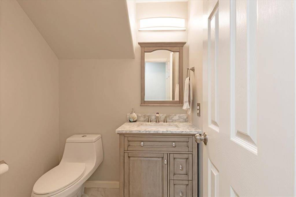 This bathroom features a modern design with a sleek toilet, a stylish vanity with a marble countertop, and a large mirror. It's well-lit with neutral tones, creating a clean and inviting space.