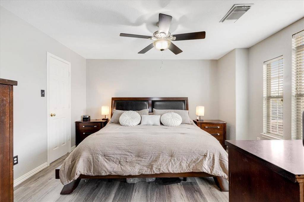 This bedroom features a spacious layout with neutral walls and sleek wood flooring. The room is well-lit with natural light from the windows.