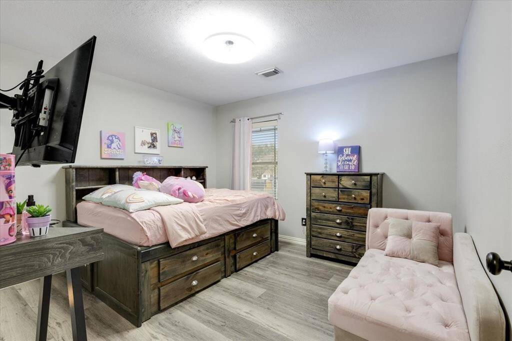This cozy bedroom features light wood flooring and soft gray walls.