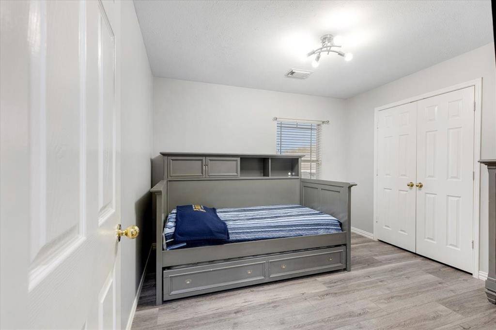 This bedroom features a modern gray daybed with storage drawers and a double-door closet.