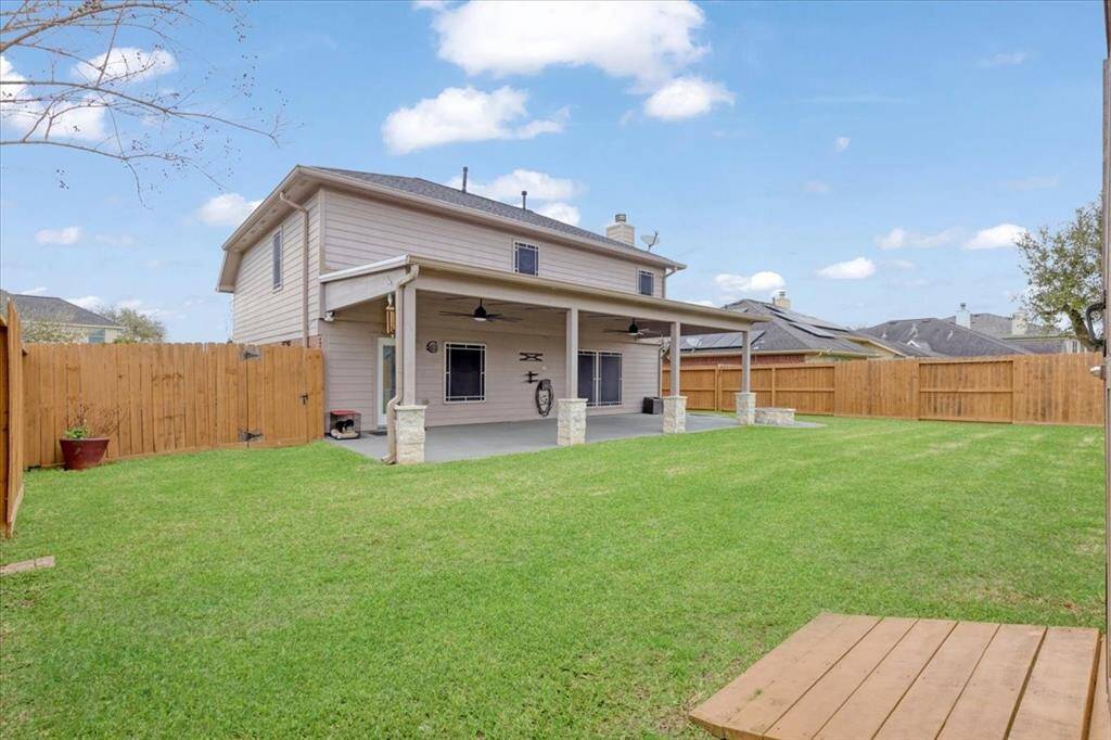 Charming two-story home with a spacious fenced backyard, featuring a large covered patio perfect for outdoor entertaining.