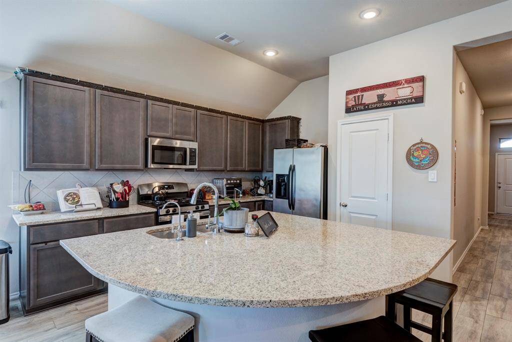 Kitchen has the extended bar feature when the home was built.  Kitchen offers wood look tile, granite tops, tile back splash, and SS GE appliances.
