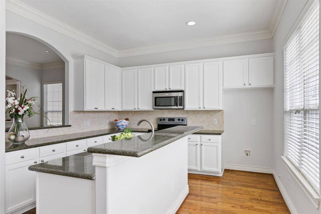 Great view of gourmet island kitchen has arch window to dining area, granite countertops, breakfast bar and lots of cabinets for storage.