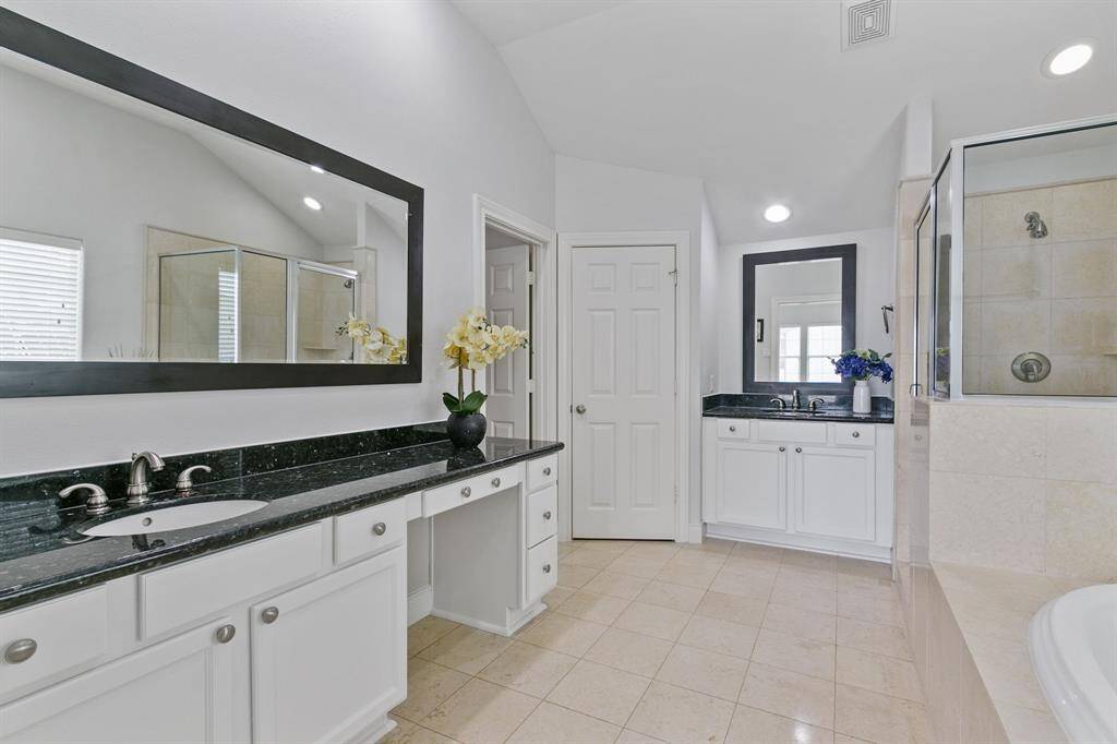 Primary bathroom is freshly painted and has tile floor, two vanities each with a sink, separate shower and garden tub with huge walk-in closet.