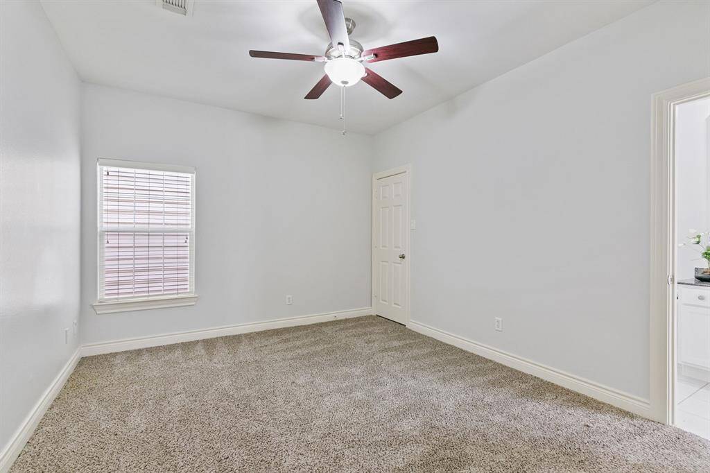 Opposite view of the first floor en-suite bedroom with carpet and ceiling fan.