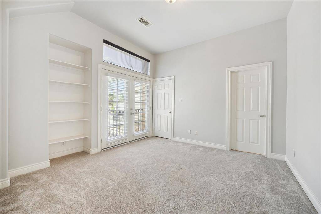 Secondary bedroom with new carpet and lovely built-in bookshelf. Small balcony located just outside the double doors.