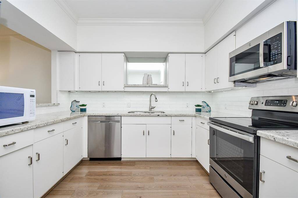 The kitchen features abundant cabinet space, sleek stainless steel appliances, and a stylish backsplash, creating a functional and visually appealing cooking area.