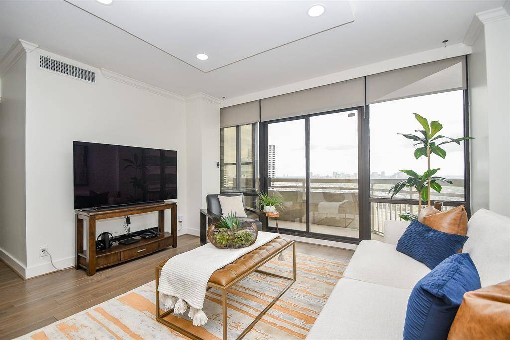 This elegant living area features crown molding, a tray ceiling, and floor-to-ceiling windows that open up to a private balcony.