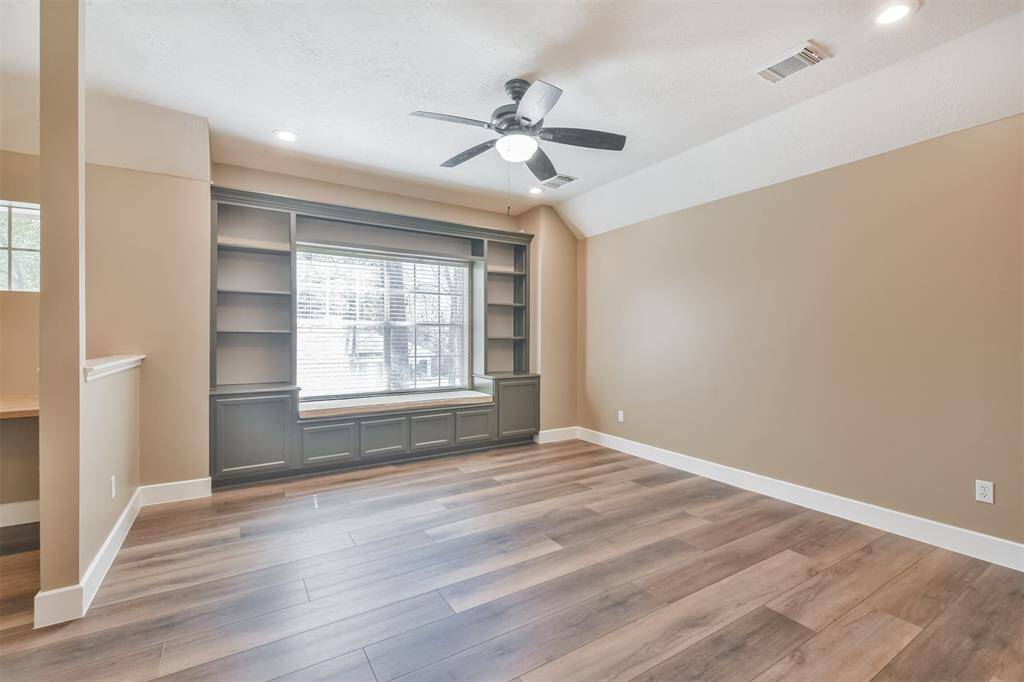 The gameroom features a wall of built-in shelves with a bench seat and custom cushion for lazy weekend reading. Updates include recent luxury vinyl plank flooring, LED lighting and  ceiling fan.