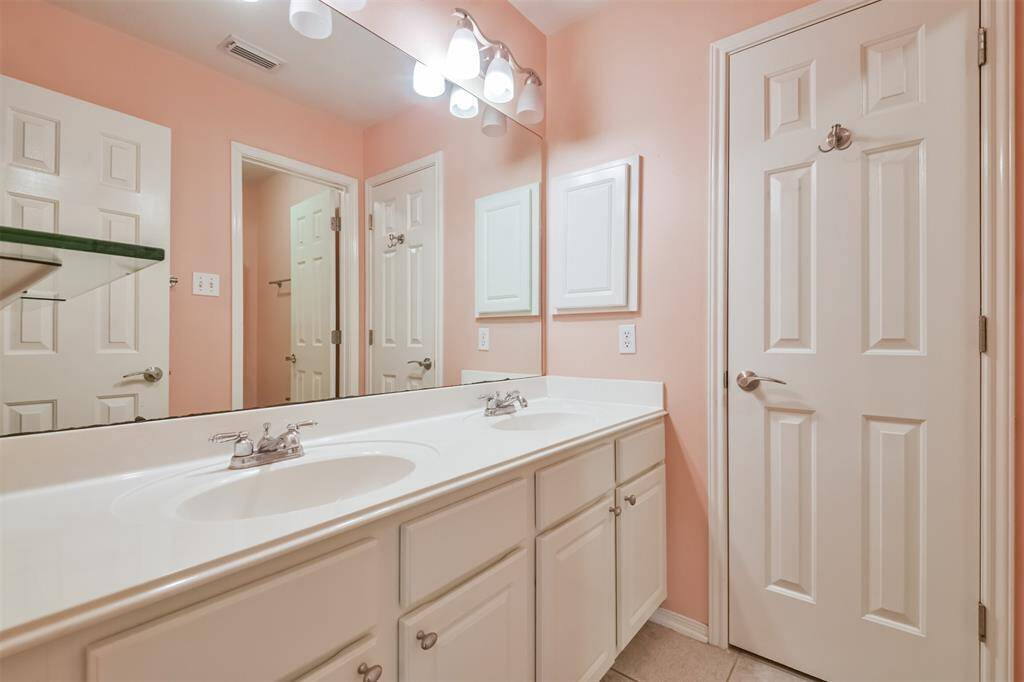 This secondary bathroom features double sinks, a linen closet and shower/tub combo.