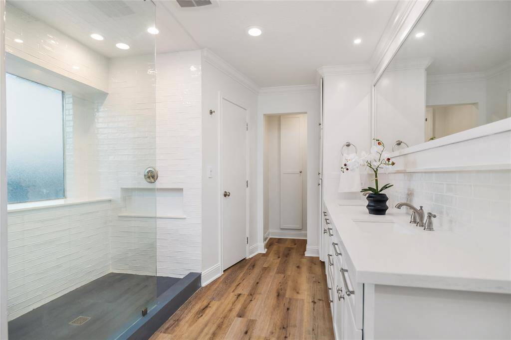 Primary bath has been tastefully updated with a walk-in shower, frames enclosure, cut-outs for shampoo and ample counter space.