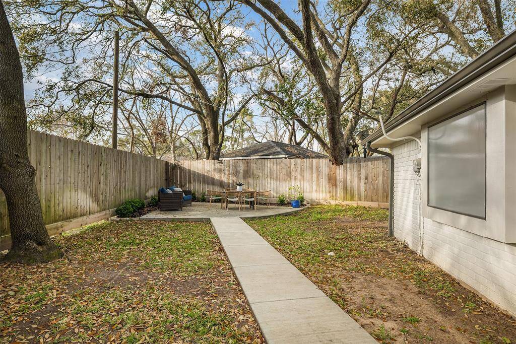 This walkway leads to a bonus patio space tucked under the serene oak trees.