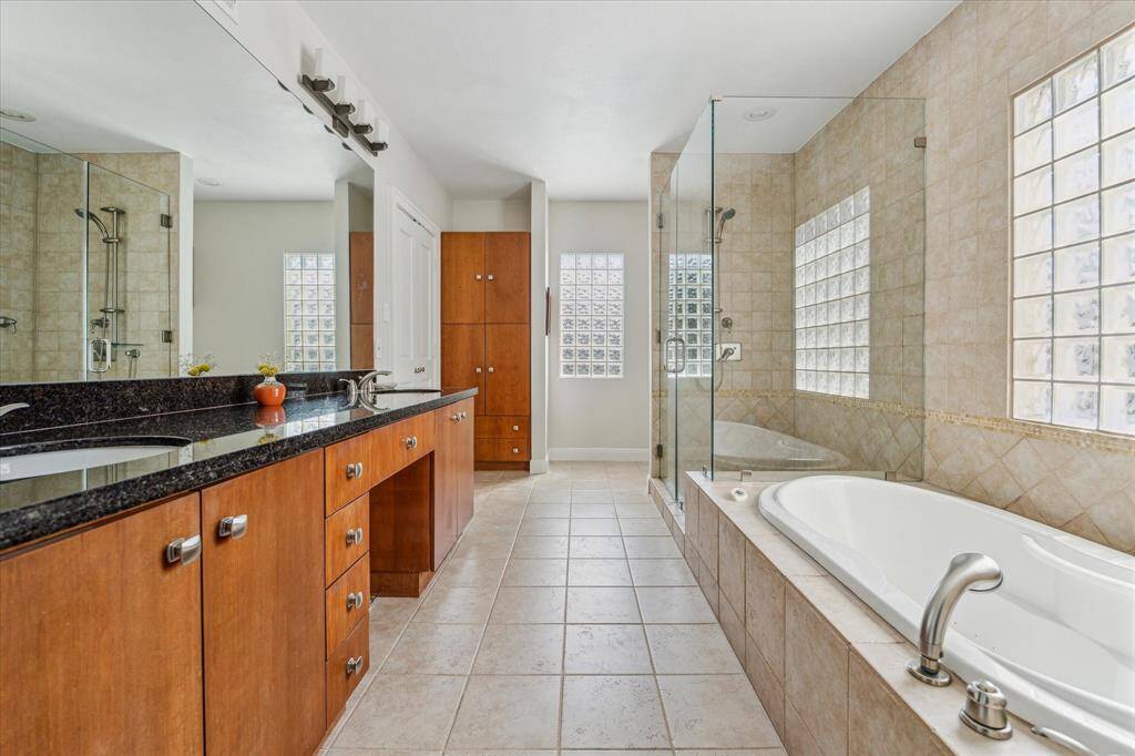 The primary bath has a deep soaking tub, a walk-in shower with glass enclosure, double sinks, a vanity and a private commode room.
