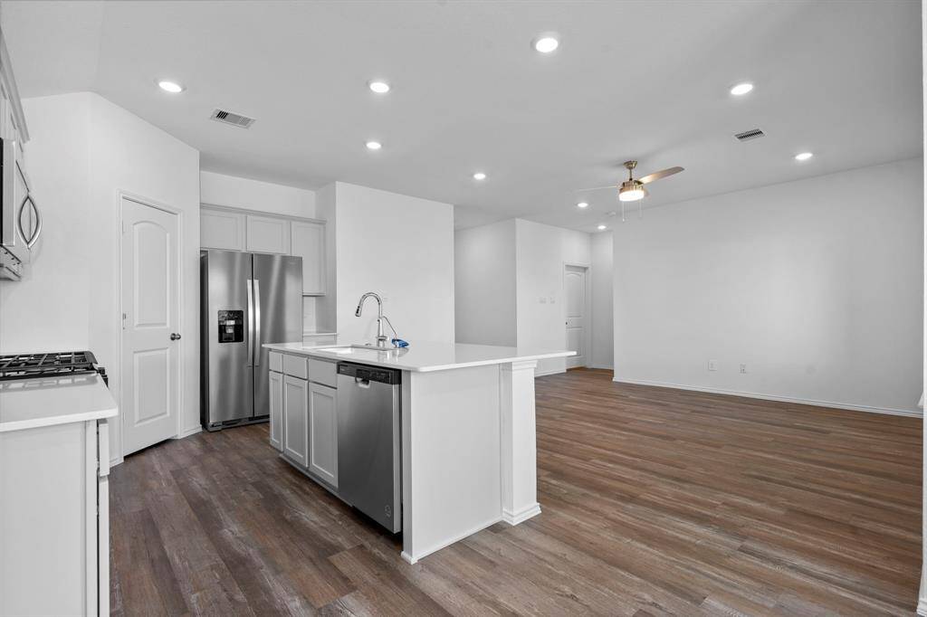 This beautifully designed space features a modern kitchen with quartz countertops, stainless steel appliances, and a large island that overlooks the spacious living area—perfect for entertaining and everyday living.