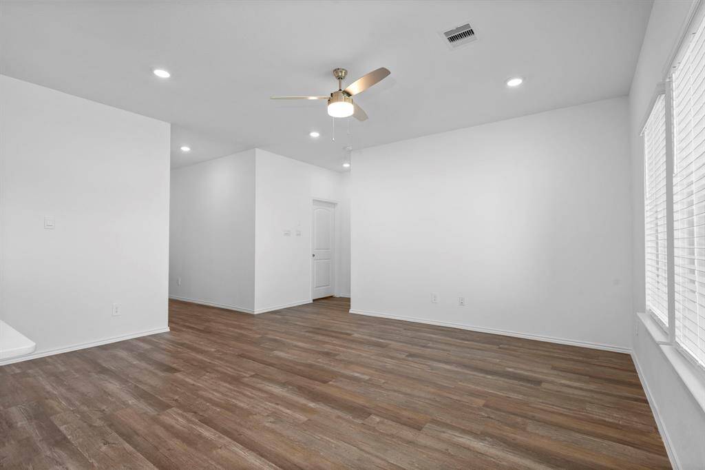 A bright and inviting space with wood-like vinyl plank flooring, recessed lighting, and a ceiling fan, creating the perfect setting for relaxation and entertainment.