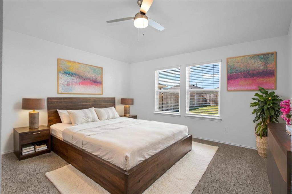 A serene and spacious primary suite with high ceilings, a ceiling fan, plush carpeting, and large windows that flood the room with natural light. **Photo is Virtually Staged to show how it would look like**