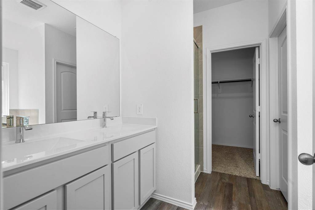This elegant primary bath features a dual-sink vanity with quartz countertops and ample storage. Wait till you discover the large walk-in closet!