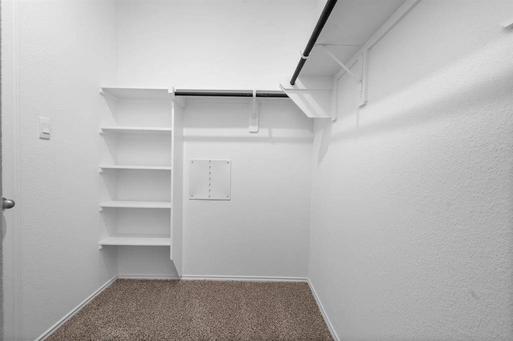 Designed for convenience, this large walk-in closet features built-in shelving, hanging racks, and plenty of space for an organized wardrobe.