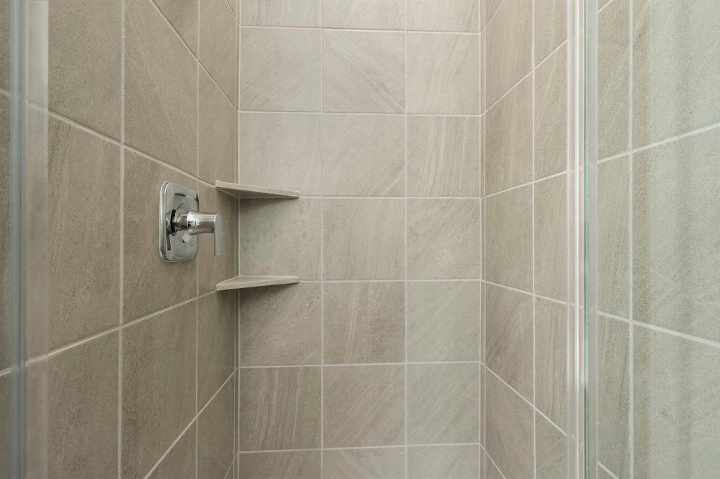 A beautifully tiled walk-in shower with built-in shelving provides a modern and functional touch to the primary bathroom.  Yes, private shower for thos shower people out there!