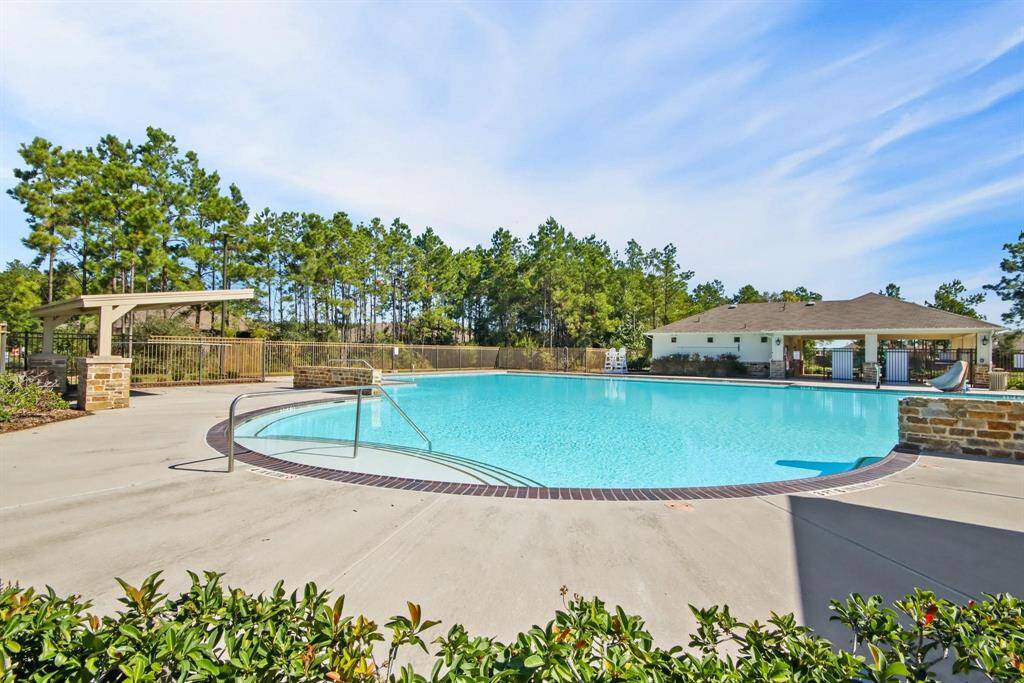A sparkling pool with a serene natural backdrop, perfect for lounging, swimming, and enjoying the warm Texas weather.