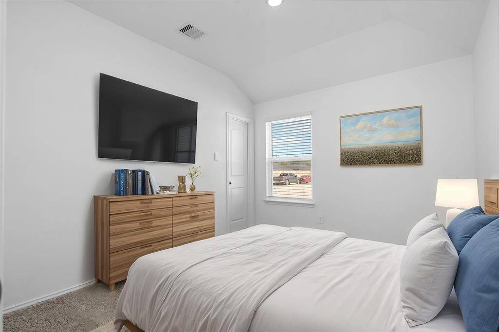 This cozy guest bedroom features soft carpeting, a vaulted ceiling, and a large window that brings in plenty of natural light. A neutral color palette and a spacious layout make this the perfect retreat for visitors. convenience and charm. **Photo is Virtually Staged to show how it would look like** VACANT AND READY FOR MOVE IN!