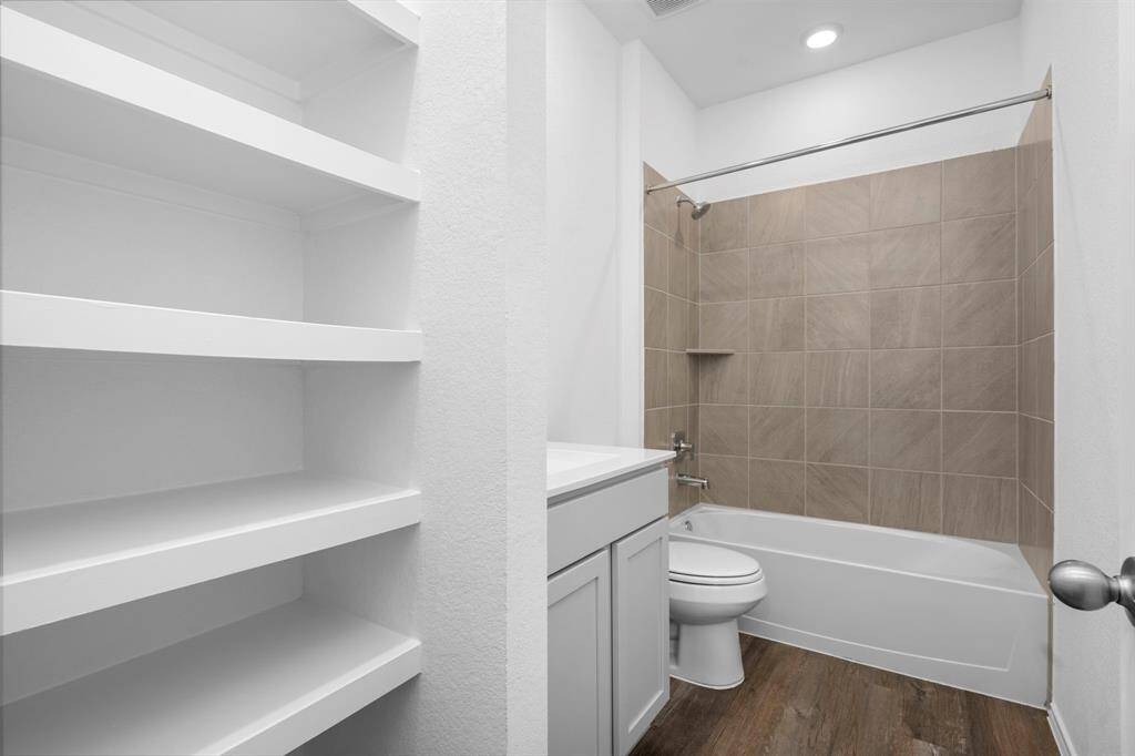 A spacious secondary bathroom with a tub/shower combo and elegant tile work, plus built-in shelving for extra storage.