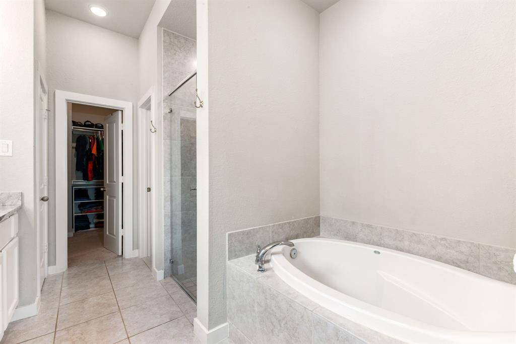 This additional view of the primary bath showcases a walk-in shower with tile surround and a separate garden tub perfect for soaking after a long day.