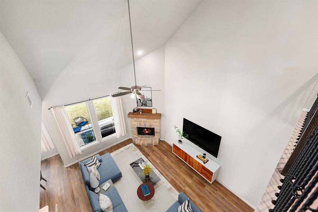Experience the airy elegance of this two-story living room featuring a stone fireplace, expansive windows for abundant natural light, and warm wood flooring,an inviting space perfect for both relaxing and entertaining. *Virtually Staged