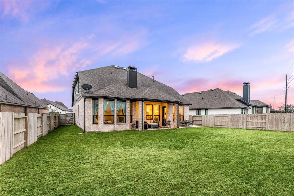 An impressive backyard oasis with plenty of green space, perfect for play, gardening, or simply unwinding under the covered patio.