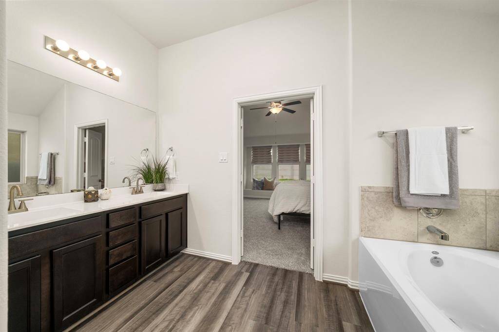 The en-suite primary bathroom offers a soaking tub, shower with tile surround, and dual vanity sinks.
