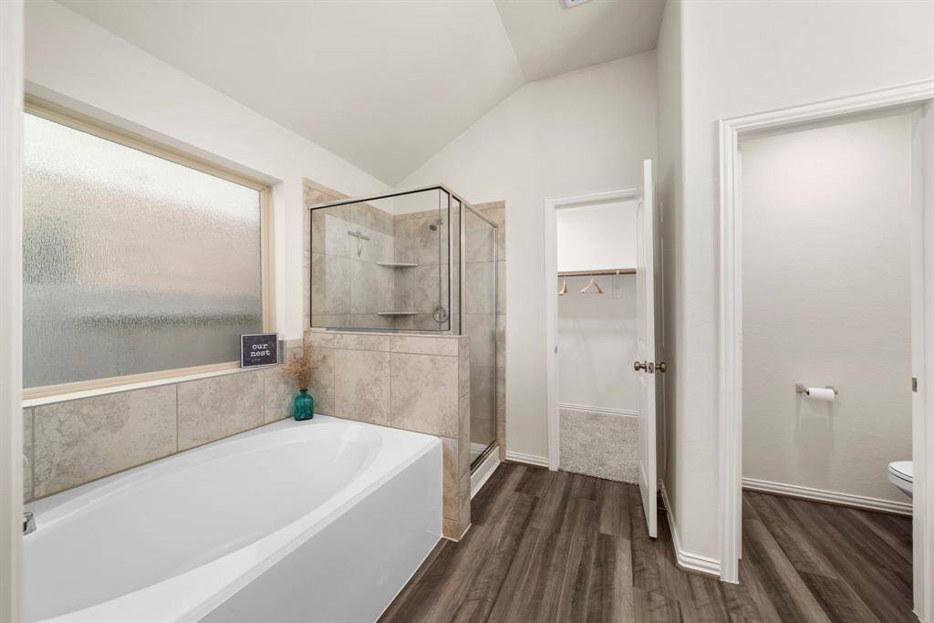 Alternate view of primary bathroom's soaking tub and shower. The large frosted window allows generous light to come in while still keeping the space private. Walk-in closet with plenty of space ahead!