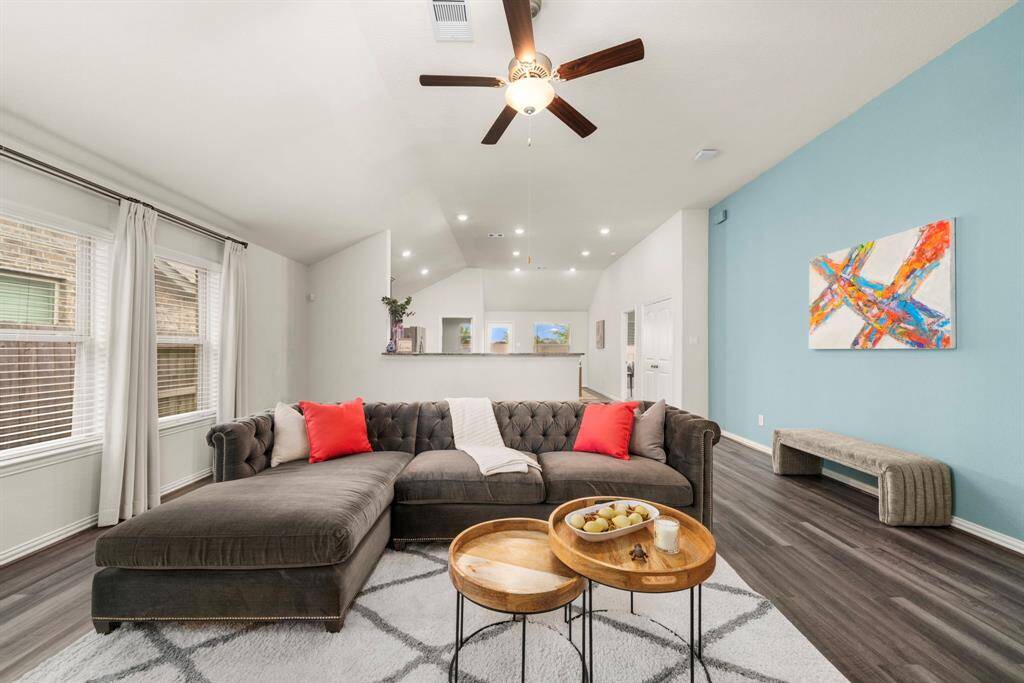 A glimpse of the interior highlighting the open floor plan and custom features, like floor to ceiling drapes on the left, and designer accent wall on the right.