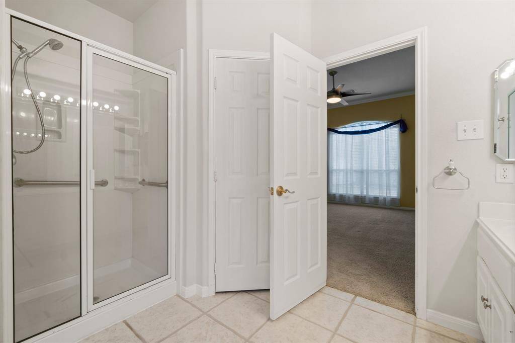 Primary bathroom features a spacious corner bathtub with a sleek, modern design. It includes a privacy-enhancing glass block window that allows natural light to fill the space.