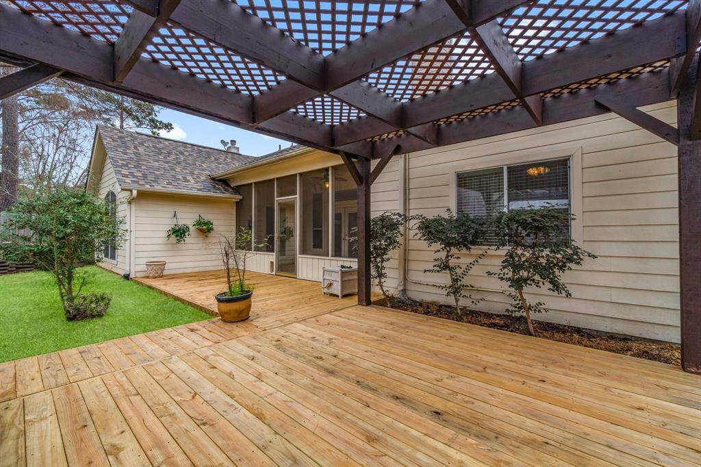 This photo showcases a backyard with a wooden deck and pergola, providing a shaded area perfect for outdoor relaxation. There's a wooden fence for privacy and a storage shed for additional space.