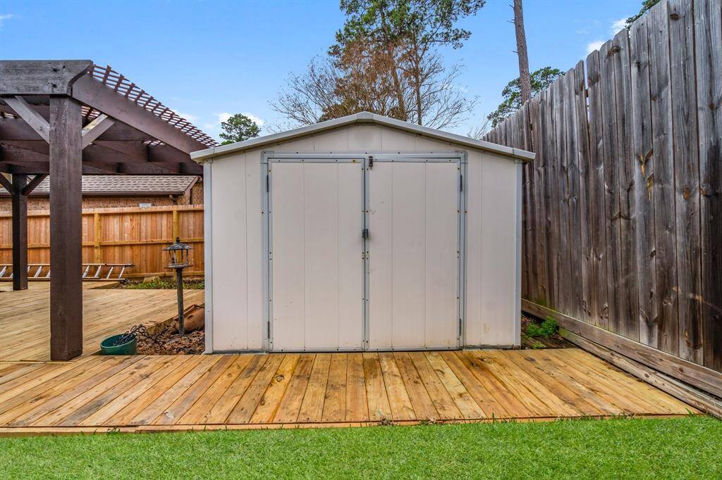 This photo showcases a charming backyard with a spacious wooden deck, partially covered by a lattice pergola. The yard features well-maintained greenery and connects to the house through a screened-in porch, creating a perfect space for outdoor relaxation and entertainment.