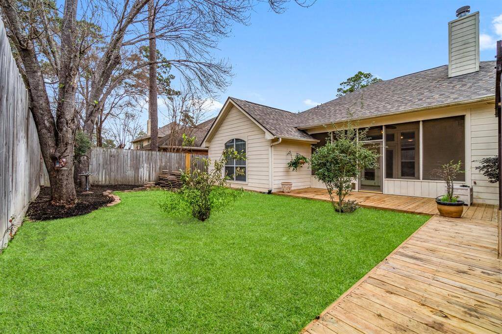 This photo shows a backyard with a wooden deck and a small storage shed. A pergola provides partial shade, and the area is enclosed by a tall wooden fence, offering privacy and a cozy outdoor space.